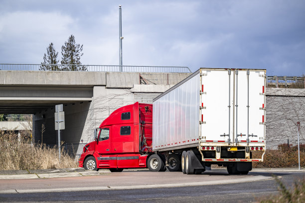 引擎盖红色大卡车半挂车运输货物的干货车半挂车在十字路口转弯，从桥下经过图片下载