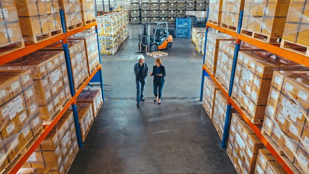 年轻的白人女性仓库工程师工人，成熟的成年女性经理在工厂仓库走动，讨论谈话。物流行业业务，产业岗位，人在工作，高角度视角图片下载