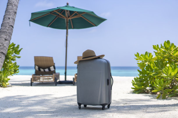 一个手提箱和一顶草帽，背景是马尔代夫的风景。旅游和热带度假的概念图片下载