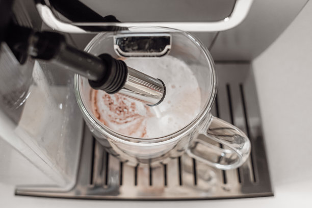 咖啡机里有牛奶泡沫的咖啡饮料图片下载