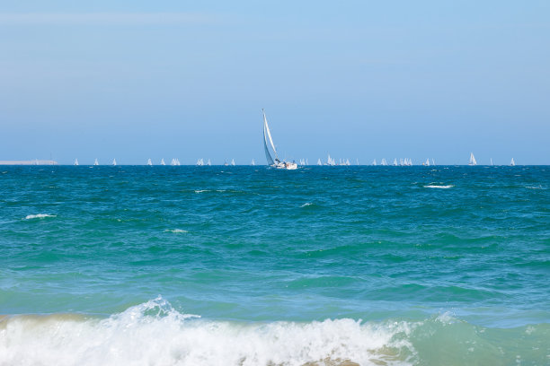 蓝色的地中海，晴朗的天空和一艘白色帆船和许多帆船。赛船会图片下载
