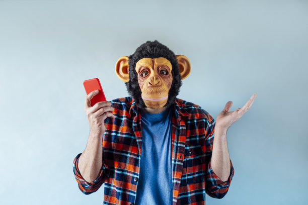 戴着猴子面具的焦虑男子使用智能手机。图片下载