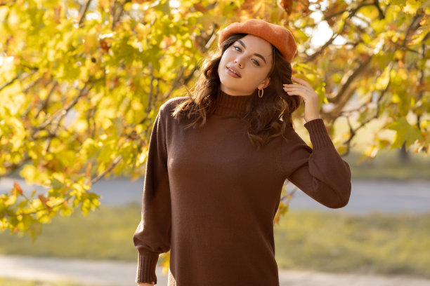 快乐的女孩在公园散步时看着相机。美丽的女人在公园放松穿着针织衣服。户外大气的时尚照片年轻美丽的女士在秋天图片下载
