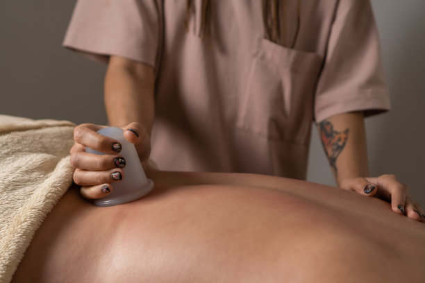 特写的按摩师做背部按摩使用硅胶真空罐。拔火罐治疗一位年轻女性的背部疼痛。健康理念，呵护身体图片下载