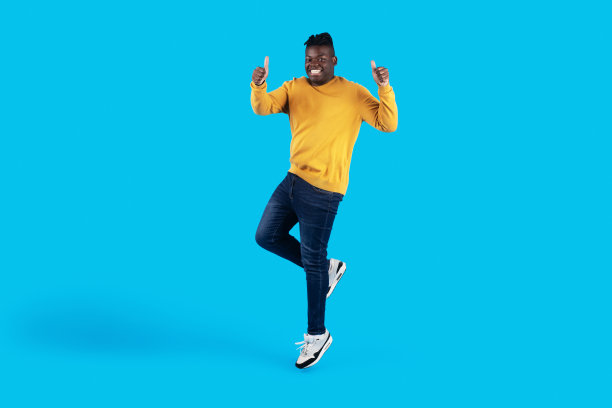 快乐的黑人年轻人跳起来，对着摄像机竖起大拇指图片下载