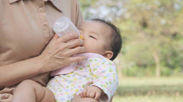 亚洲母亲抱着她的女婴用奶瓶喂养。图片下载
