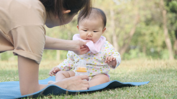 年轻的亚洲母亲从婴儿奶瓶里喝完牛奶后，擦拭女儿嘴里的奶渍。图片下载