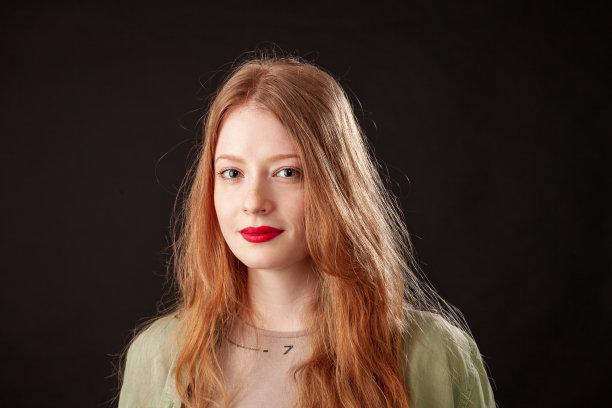 一个迷人的年轻红头发女人的特写照片，在黑色的背景上涂着红色的口红图片下载