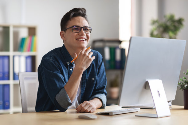 灵感的概念。微笑的年轻商人坐在工作场所，看向别处图片下载