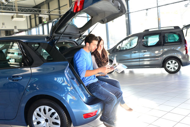 一对年轻夫妇在一家汽车经销商的展厅里购买和测试汽车图片下载