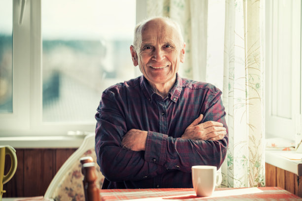 快乐的微笑积极的老人坐在餐桌在厨房图片下载