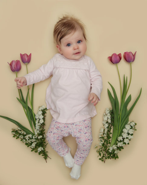 可爱的五个月大的婴儿与粉红色的春季郁金香。春天的使者。婴儿和婴儿里程碑会议。春天的作文。新生儿照片。3月8日或复活节明信片的概念。图片下载