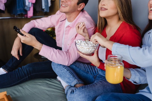 一群拉丁美洲朋友坐在床上看电视或电影在墨西哥拉丁美洲，西班牙人图片下载