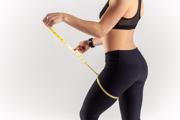 未知的运动金发女子抱厘米在她的腿上，检查运动马拉松后的结果。图片下载