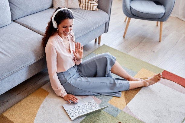 微笑的女人坐在家里的地板上工作在线挥手视频聊天图片下载