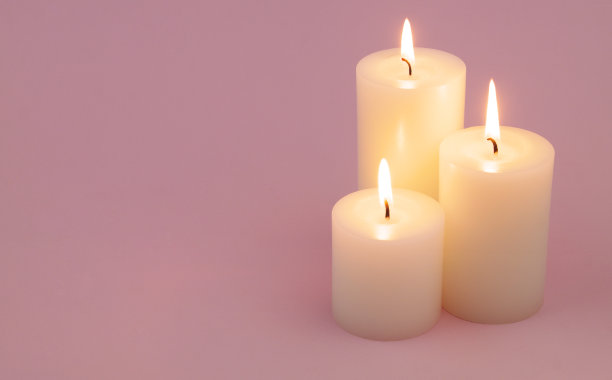 白色的蜡烛燃烧在粉红色的背景。图片下载