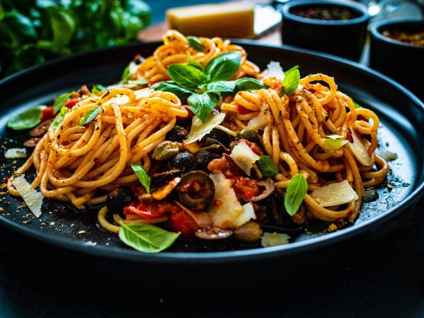 意大利肉酱面-意大利面加上切碎的猪肉和番茄酱放在黑色的桌子上图片下载