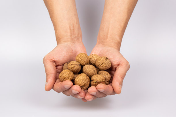 灰色背景上，两只男性手拿着核桃。收获的概念。俯视图特写。图片下载