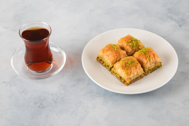 传统的开心果果仁蜜饼配土耳其茶。一盘黑色背景的果仁蜜饼图片下载