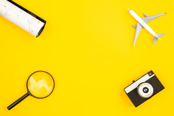 飞机模型，地图，相机和放大镜在黄色背景，平铺。图片下载