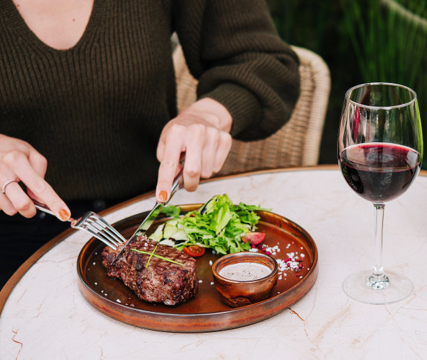 一个女孩在餐厅的露台上切煎牛排图片下载