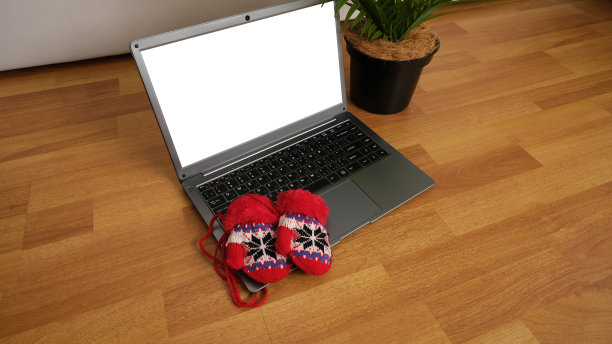 带有圣诞图案的红色手套放在笔记本电脑键盘上。图片下载