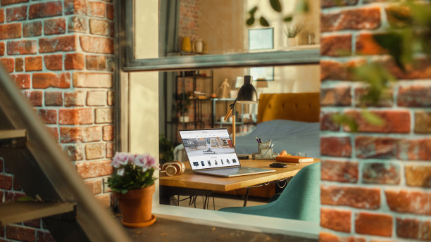 笔记本电脑与网上购物网站显示站在桌子上的时尚客厅。布鲁克林风格的褐砂石建筑窗外的风景。在家工作概念。图片下载