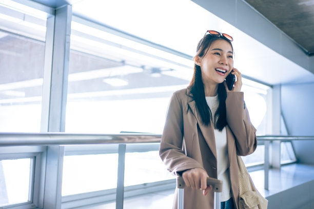 亚洲年轻女乘客在机场打电话。迷人美丽的女游客朋友心情愉快，兴奋地乘飞机出国旅游度假旅行图片下载