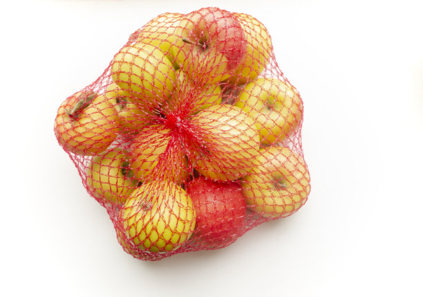 苹果在购物网上。生态购物-可重复使用的网。在白色的背景上是一个红色的网格和黄色的苹果。包装产品——网格苹果。图片下载