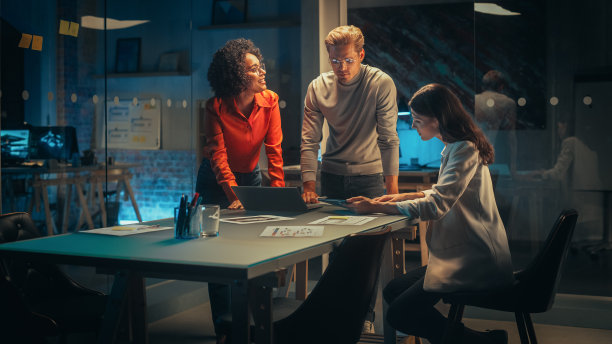 不同的年轻经理团队晚上在办公室开会讨论工作。成功的商业伙伴谈论营销活动，熟悉公司报告图片下载