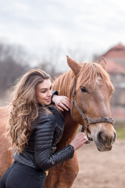 年轻女子抱着她的棕色马，看着镜头。图片下载