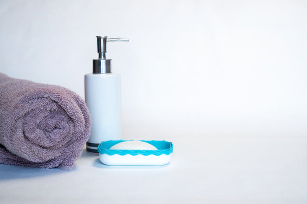 一条毛巾，白色背景上的液体和固体肥皂。发短信的地方。特写镜头图片下载