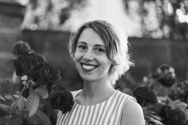 金发女人在背景上的玫瑰灌木。花园。春天的背景图片下载