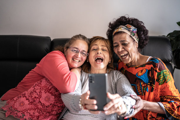 朋友们在家里的客厅里用手机自拍或拍摄图片下载