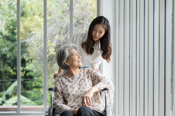 年轻的亚洲女护士照顾老年妇女病人小心轮椅上。快乐的微笑女性照顾老年妇女在轮椅上亲切地在养老院图片下载