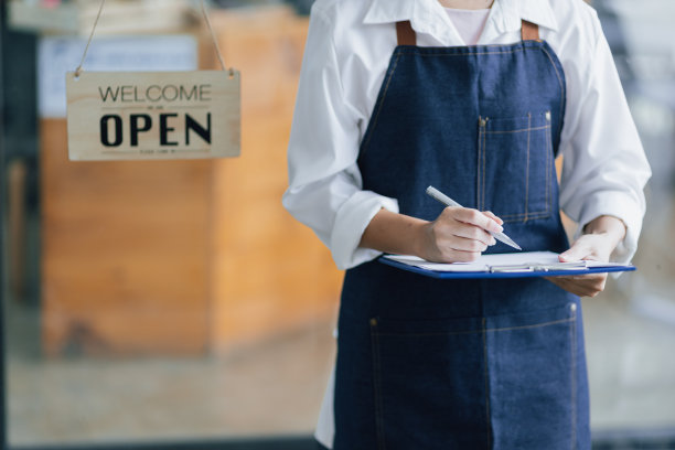 接待员在一家新开张的餐厅工作。拿着记事本的服务员正等着写下餐单。图片下载