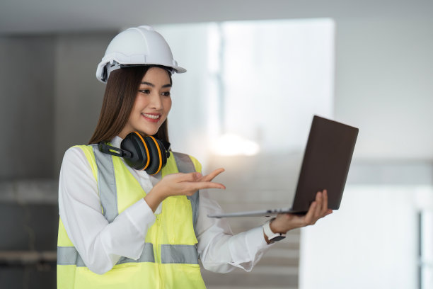 照片微笑女工程师与笔记本电脑在建筑工地图片下载