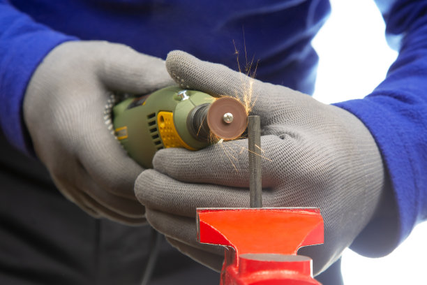 工人用雕刻钻加工金属。工作的德梅尔雕刻电动工具。工业金属加工图片下载