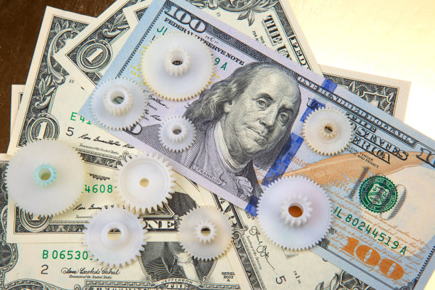美元背景上的塑料齿轮。商业互动的概念，以实现财务上的成功图片下载