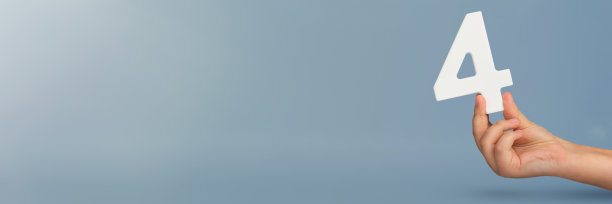 4号在手上。手握白色数字4在蓝色背景与复制空间。第四个概念。生日4岁，四年级，每周工作四天图片下载