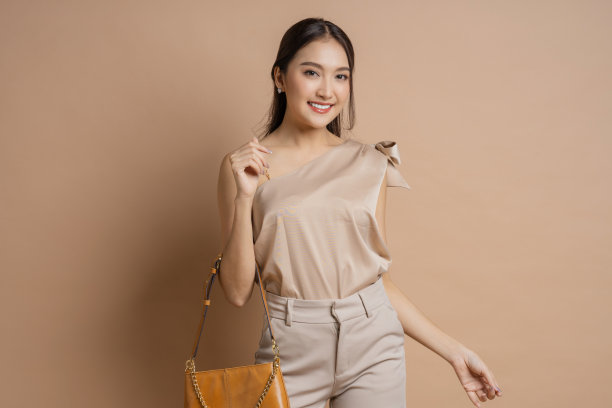 自信，有魅力，时尚的亚洲女性，奢华的衣服，布料，魅力，微笑，开朗，享受积极的情绪，手势，热情的欢迎，看看相机人像工作室拍摄的棕色背景图片下载