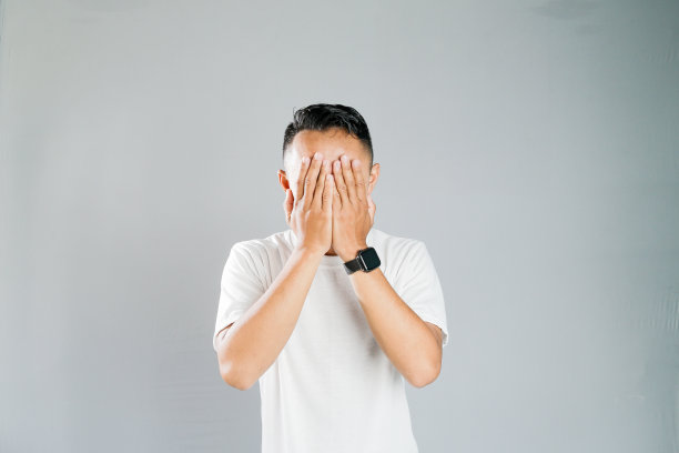 一个年轻的亚洲人正用手捂着脸图片下载