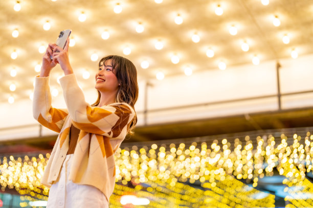 年轻的亚洲女子使用手机拍摄城市景观在城市的夜晚。图片下载