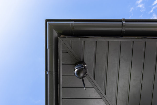 圆形无线摄像头安装在屋顶的角落里，监控一个独栋住宅。图片下载