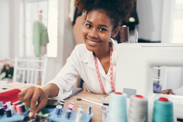 快乐美丽的非裔美国妇女时装设计师的衣服工作与缝纫在自己的服装工作室或精品店图片下载