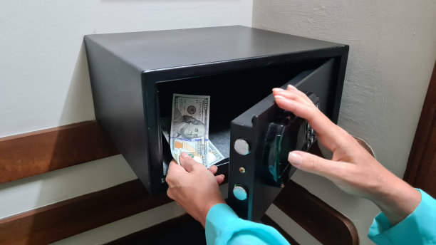一名女子在酒店门上的金属保险柜门上拨密码，拿美元图片下载