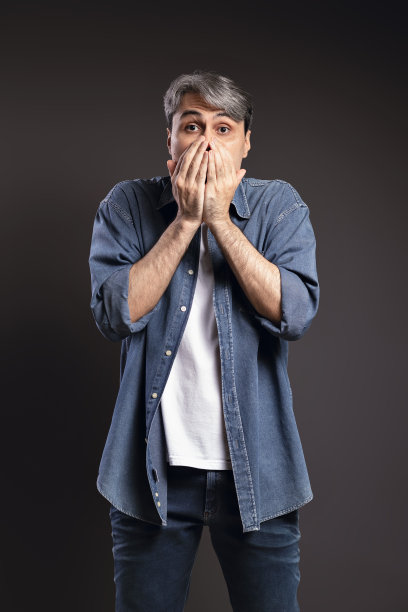 巴西男子的肖像，穿着纽扣衬衫和牛仔裤，惊讶，手在脸上，与灰色的头发-彩色照片-巴西图片下载