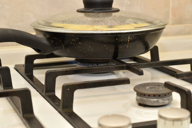 煤气炉上有一个带盖子的煎锅。图片下载