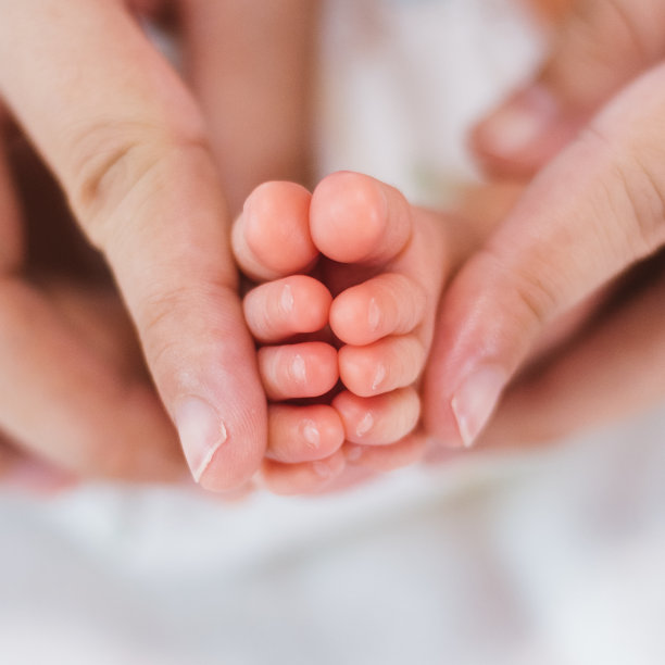 刚出生的婴儿脚踩在白色毯子上。母亲抱着新生婴儿的脚。母婴概念。图片下载