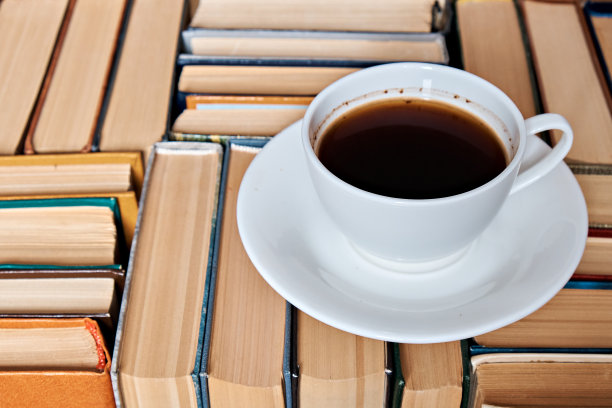 一杯咖啡放在折叠的精装书上，侧视图。教育的概念。近距离图片下载